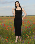 Woman in a black dress standing in a field of wildflowers