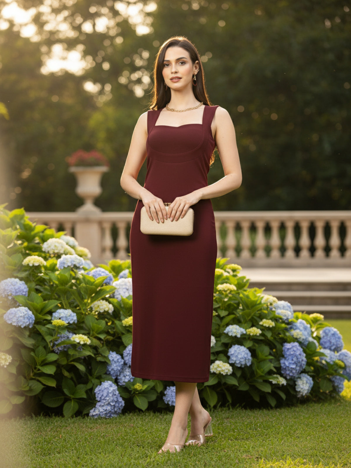 Woman in a burgundy dress standing against a beige wall with a chair and decorative plant.